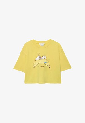 Žlté krátke tričko so Snoopym ležiacim na veľkej banánovej grafike a textom "PEANUTS SINCE 1950" pod ňou.