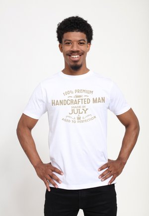 T-shirt en coton blanc avec texte doré : "100 % Premium fait main, créé en juillet, vieilli à la perfection." Encolure ronde, manches courtes.