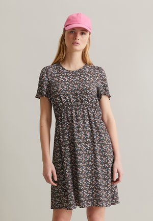 Robe à manches courtes avec un motif floral sombre comportant des fleurs roses et bleues. Accompagnée d'une casquette rose clair. Design décontracté et léger.