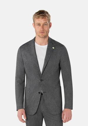 Grijze textuurblazer met twee voorkruiden, revers, en een enkele knoopsluiting. Draagt over een wit T-shirt.