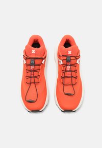 Rode sportieve sneakers met een bovenkant van mesh, elastische veters, een gevoerde kraag en een gewatteerde witte zool. Opvallend merklogo op de tong.