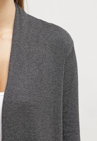 Szary kardigan wykonany z miękkiej dzianiny, z otwartym przodem i długimi rękawami. Teksturowane wykończenie dodaje subtelnej głębi.