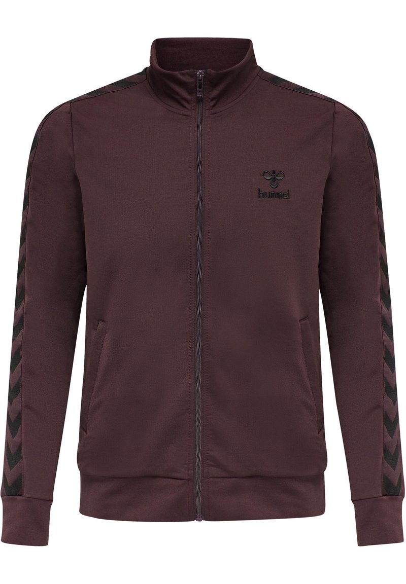 Chaqueta marrón con collar alto, cierre completo, con patrones en forma de chevron negros en las mangas y un pequeño logo negro en el pecho. Textura suave.