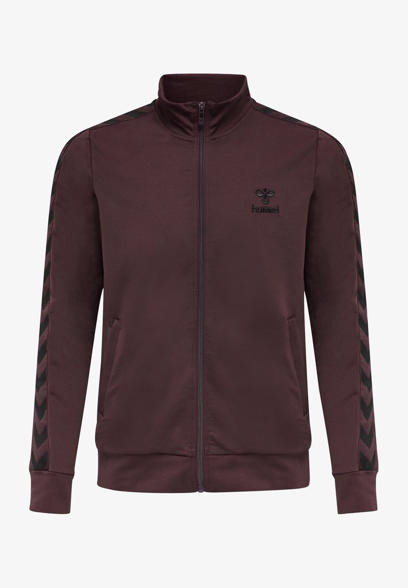 Chaqueta marrón con collar alto, cierre completo, con patrones en forma de chevron negros en las mangas y un pequeño logo negro en el pecho. Textura suave.