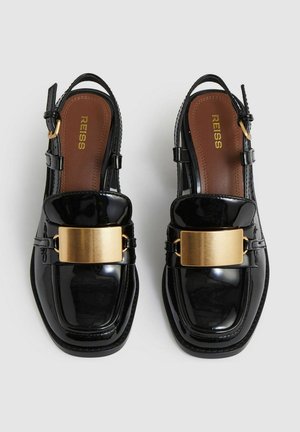 Czarne lakierowane buty slingback z kwadratowym noskiem, z wykończeniem z metalowego złota oraz brązową wkładką. Posiadają regulowany pasek wokół kostki.