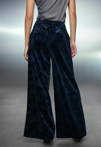 Kalhoty s širokými nohavicemi vyrobené z námořnického sametu, s texturovaným květinovým vzorem, zadními kapsami a hladkým pasem.