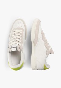 Zapatillas blancas y beige con acentos en verde claro en el talón, zapato izquierdo visto desde arriba, zapato derecho de perfil, sobre un fondo blanco.
