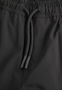 Czarne sportowe szorty wykonane z lekkiego materiału, z elastycznym pasem i sznurkiem do regulacji dopasowania oraz subtelną fakturą.