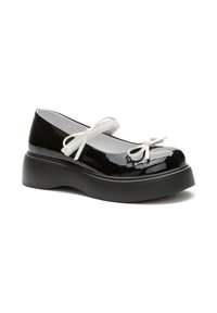 Scarpe in vernice nera con punta rotonda, dotate di dettagli in fiocco bianco e una spessa suola piattaforma nera.