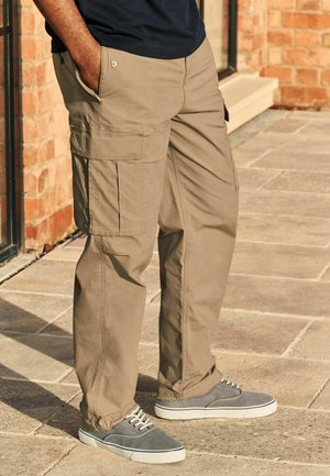 Beige cargo pants with multiple side pockets, made of lightweight fabric. Paired with gray sneakers featuring white soles.