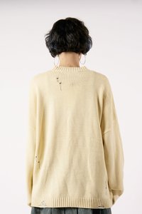 Bežinis per didelis megztinis su tekstūrine mezgimo struktūra, turintis išskirtinę plyšio detalę ant nugaros, su būgno forma apykakle ir apvadu.