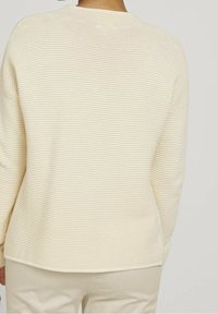Cremefarbener Strickpullover mit strukturiertem Rippenmuster, rundem Ausschnitt und leicht lässiger Passform.