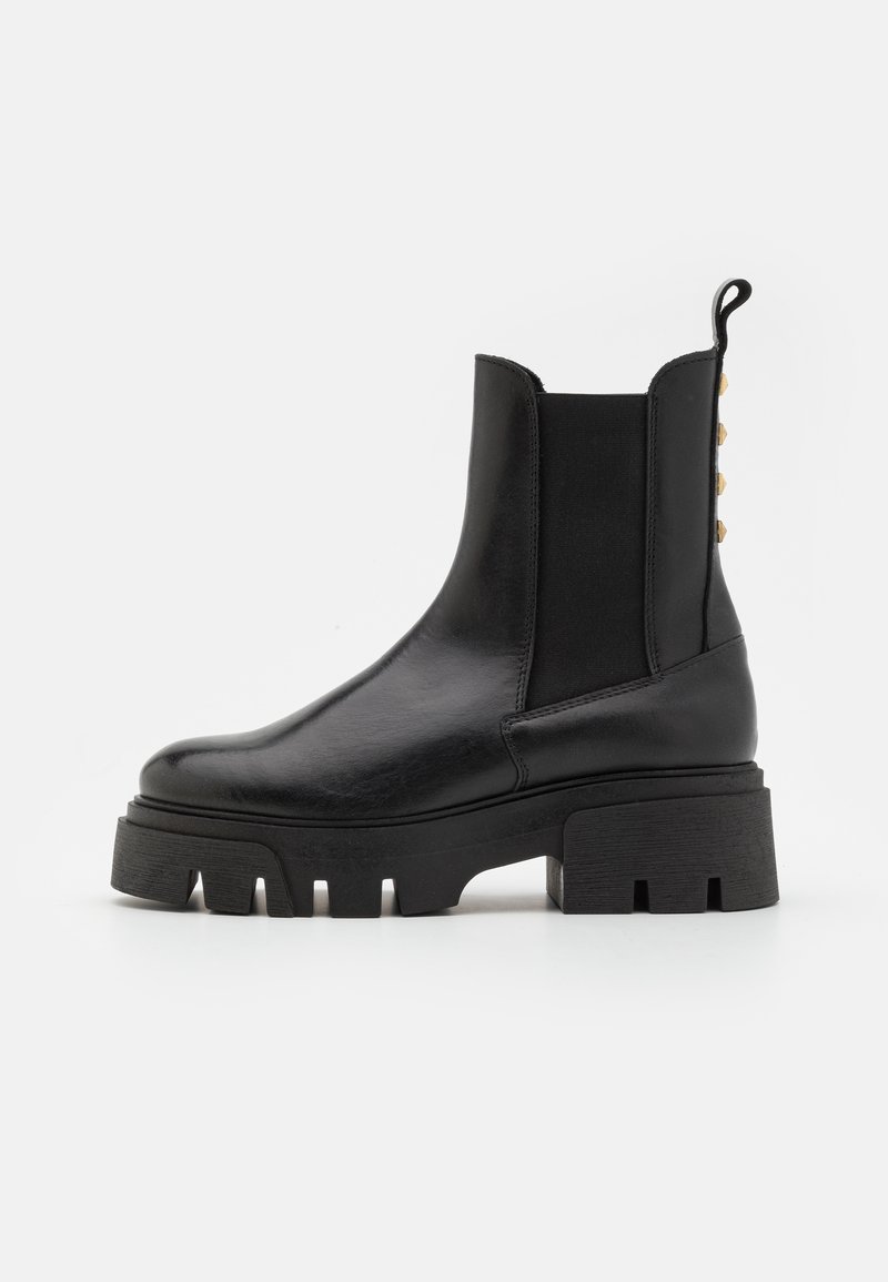 Bottine noire en cuir avec semelle à crampons épaisse, panneaux latéraux élastiques, languette de tirage et petits clous dorés à l'arrière.