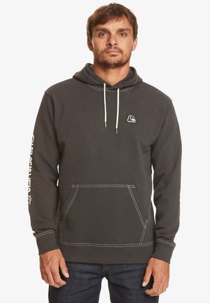 Hoodie gris foncé en mélange de coton avec une poche avant, cordons de serrage blancs et coutures contrastantes. Logo sur la poitrine et la manche.