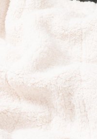 Soft, fluffy throw blanket in off-white fleece, textured with raised fibers creating a cozy, inviting appearance.