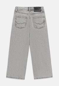 Pantalons en denim gris avec une coupe large, dotés de deux poches arrière et d'un label noir à la taille. Détails de couture simples sur les poches.