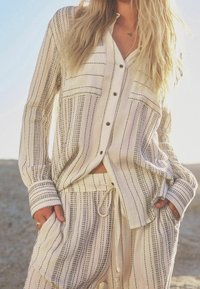 Chemise légère en lin beige à rayures, avec deux poches poitrine et fermeture à boutons ; associée à un pantalon fuselé assorti doté d'un cordon de serrage.