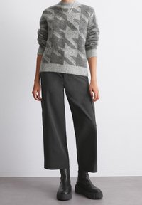 Gray knitted sweater with houndstooth pattern, paired with dark wide-leg trousers. Features chunky black platform boots. Simple neckline design.
