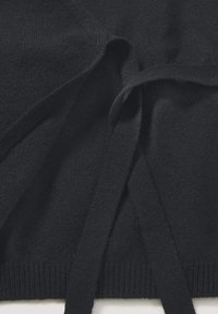 Dunkler Strickcardigan mit langen Bindebändern. Weiche Textur, gerippter Saum und dezenter Stretch. Keine sichtbaren Muster. Hauptfarbe ist tiefschwarz.