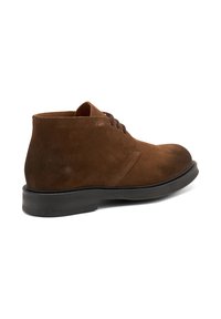 Stivali alla caviglia in suede marrone con design a lacci e suola in gomma, dotati di punta arrotondata e dettagli di cucitura minimal.