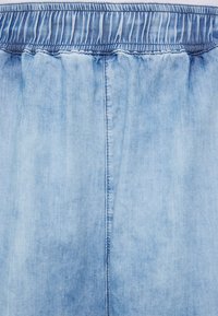 Pantalones de mezclilla de color azul claro con una cinturilla elástica, que presentan una textura suave y costuras verticales a lo largo del centro.