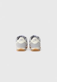 Nike sneakers feature a gray suede upper, white accents, a cushioned sole, and a textured rubber outsole with a gum finish.