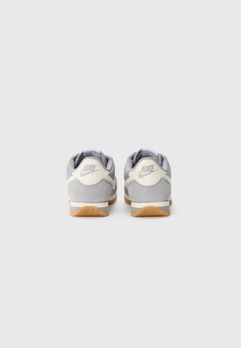 Nike-Sneaker verfügen über ein graues Wildleder-Obermaterial, weiße Akzente, eine gepolsterte Sohle und eine strukturierte Gummisohle mit einer Gummi-Oberfläche.