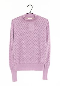 Lila stickad tröja med diamantmönster, ribbad halsringning och mudd, samt en volangdetalj vid kragen. Hänger från en svart krok.