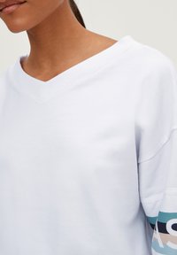 Witte V-hals sweatshirt met geribbelde halslijn en gekleurde accenten op de mouwen, met een zachte textuur en een relaxte pasvorm.