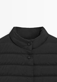 Colletto di giacca imbottita nera con design arrotondato, caratterizzato da linee trapuntate orizzontali e due grandi bottoni neri per la chiusura.