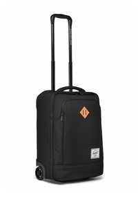 Valise noire souple avec poche avant, patch en cuir en forme de diamant, poignée extensible et deux roues pour le transport.