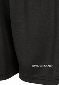 Sorte atletiske shorts lavet af tekstureret stof med en glat overflade. Har et hvidt "ENDURANCE" logo nær kanten og syede kanter.