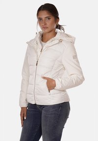 Giacca a vento bianca con zip anteriore, cappuccio attaccato e tasche laterali. Presenta hardware in tono oro e una texture trapuntata.