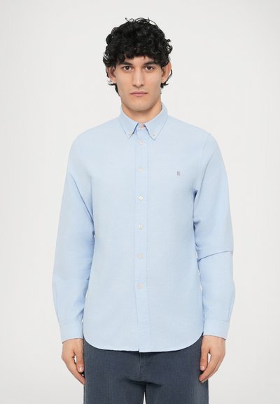 Chemise boutonnée bleu clair à manches longues, confectionnée dans un tissu texturé. Présente un petit logo, un ourlet arrondi et des détails de boutons contrastants.