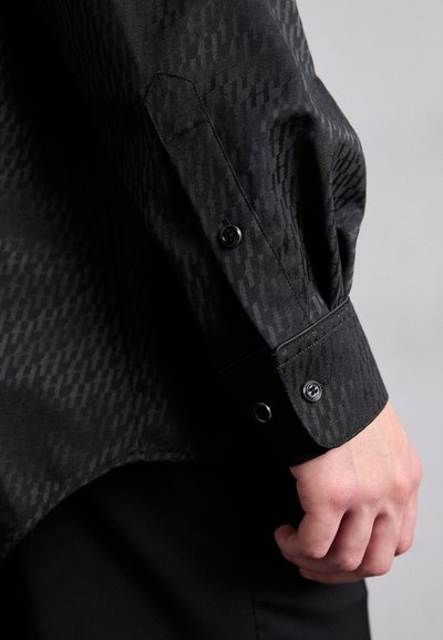 Schwarzer gemusterter Hemdmanschette mit einer glatten Textur, ausgestattet mit schwarzen Knöpfen und einem taillierten Schnitt. Ein subtil geometrisches Design erhöht das visuelle Interesse.