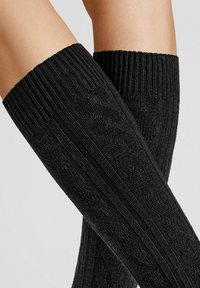 Schwarze knielange Socken mit ribbeliger Textur und subtilen geometrischen Mustern, mit einem anliegenden oberen Abschluss für sicheren Halt.