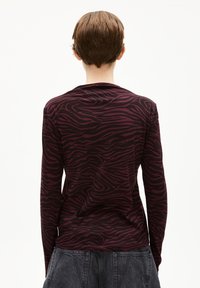 Langarmshirt in dunkelbordeaux mit einem schwarzen Zebra-Streifenmuster. Glattes Material mit taillierter Passform, Rundhalsausschnitt und ohne sichtbare Hardware.