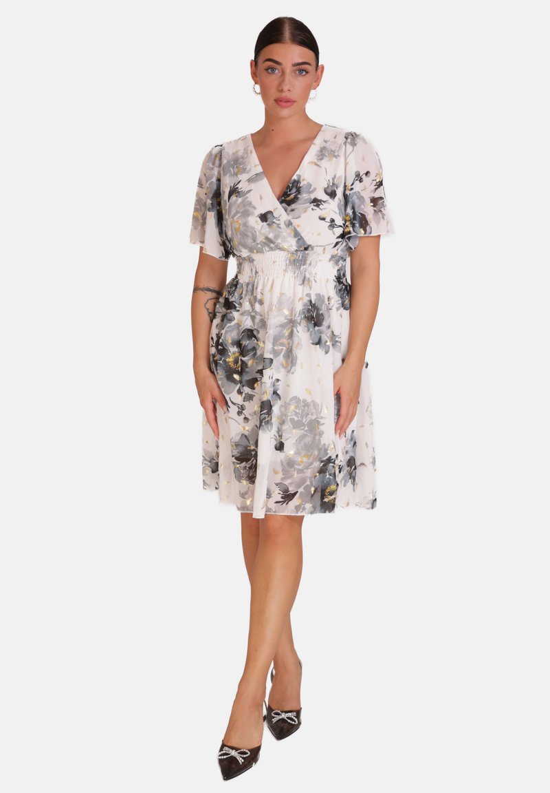 Vestido floral en tejido ligero, con diseño envolvente, mangas cortas y cinturilla elástica. Los colores incluyen blanco, gris y detalles en dorado.