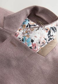 Lila strukturierter Stoff mit einem blumengemusterten Innenfutter in verschiedenen Rosatönen und Blau. Enthält ein markantes Kragen-Design.