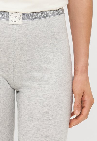 Sive tajice s mekanom teksturom i uskim dizajnom. Imaju brendirani elastični pojas s natpisom "Emporio Armani" u tamnijoj sivoj boji.