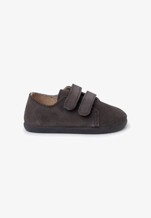 Chaussure en daim brun foncé avec deux bandes auto-agrippantes, bout rond et intérieur doux. La semelle est noire et plate, offrant un design décontracté.
