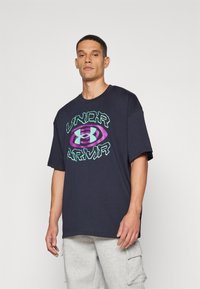 Mornarska pamučna majica s oversized krojem, s odvažnim zelenim i ljubičastim grafičkim logotipom "Under Armour" na sredini, okrugli izrez, kratki rukavi.