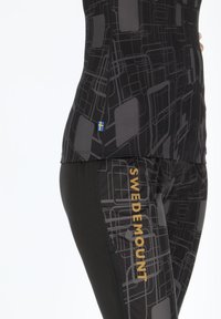Set di abbigliamento attivo nero composto da una maglietta con un motivo geometrico grigio e leggings con un stampa simile e logo dorato "SWEDEMOUNT".