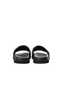 Sandali neri con la suola piatta realizzati in materiale sintetico liscio, design minimalista, punta aperta e suola texturizzata per una migliore aderenza.