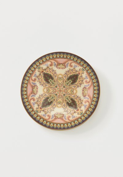 Assiette décorative ronde avec des motifs floraux et de feuilles symétriques complexes en vert, violet, pêche et or sur un fond crème.