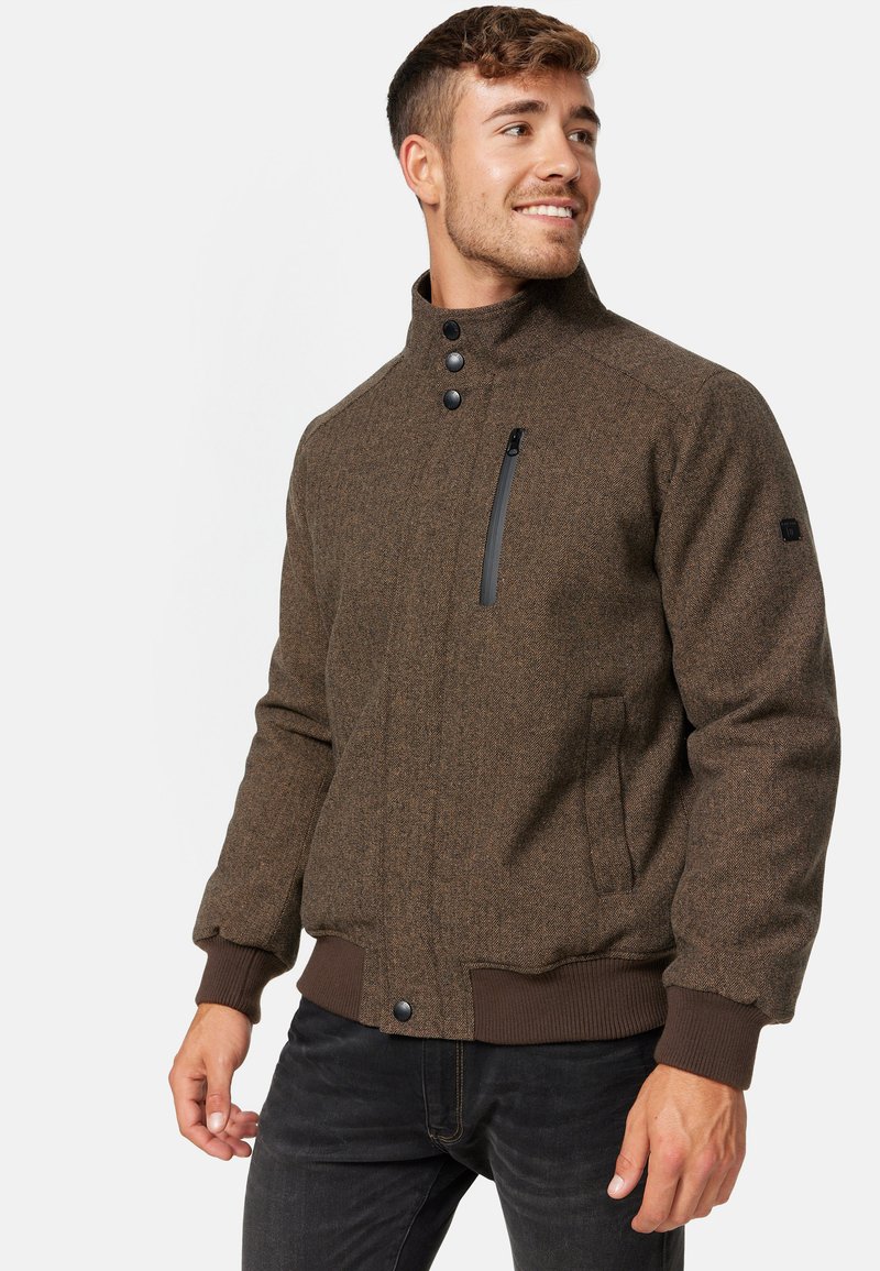 Braune, strukturierte Jacke mit hohem Kragen, Druckknöpfen und einer mit Reißverschluss versehenen Brusttasche. Gerippte Bündchen und Saum. Vordertaschen.