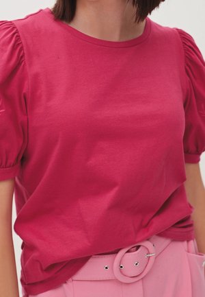 Haut fuchsia à manches courtes avec des manches bouffantes, en coton. Doté d'un col rond et d'une coupe décontractée, associé à une ceinture rose.