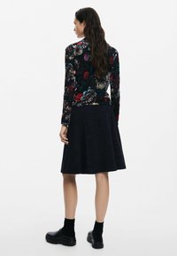 Mustandusega lilleline pikakäiseline ülikond mustas värvuses, millel on mitmevärvilised mustrid. Kombineeritud kindla, volangse tumesinise seelikuga. Mustad paksud jalanõud lõpetavad välimuse.