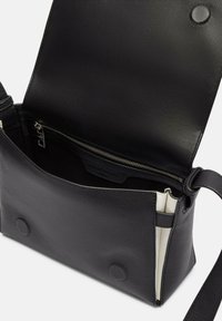 Czarna skórzana torba na ramię z teksturowanym wykończeniem. Posiada zapinaną na zamek wewnętrzną kieszeń oraz zapięcie na magnes, a także pasek na ramię.