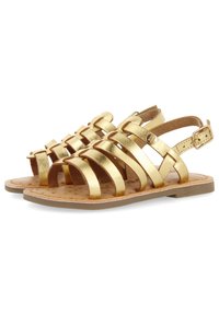 I sandali metallici oro presentano numerose cinghie diagonali, una cinghia alla caviglia regolabile e una soletta imbottita con un delicato motivo. Suola piatta.
